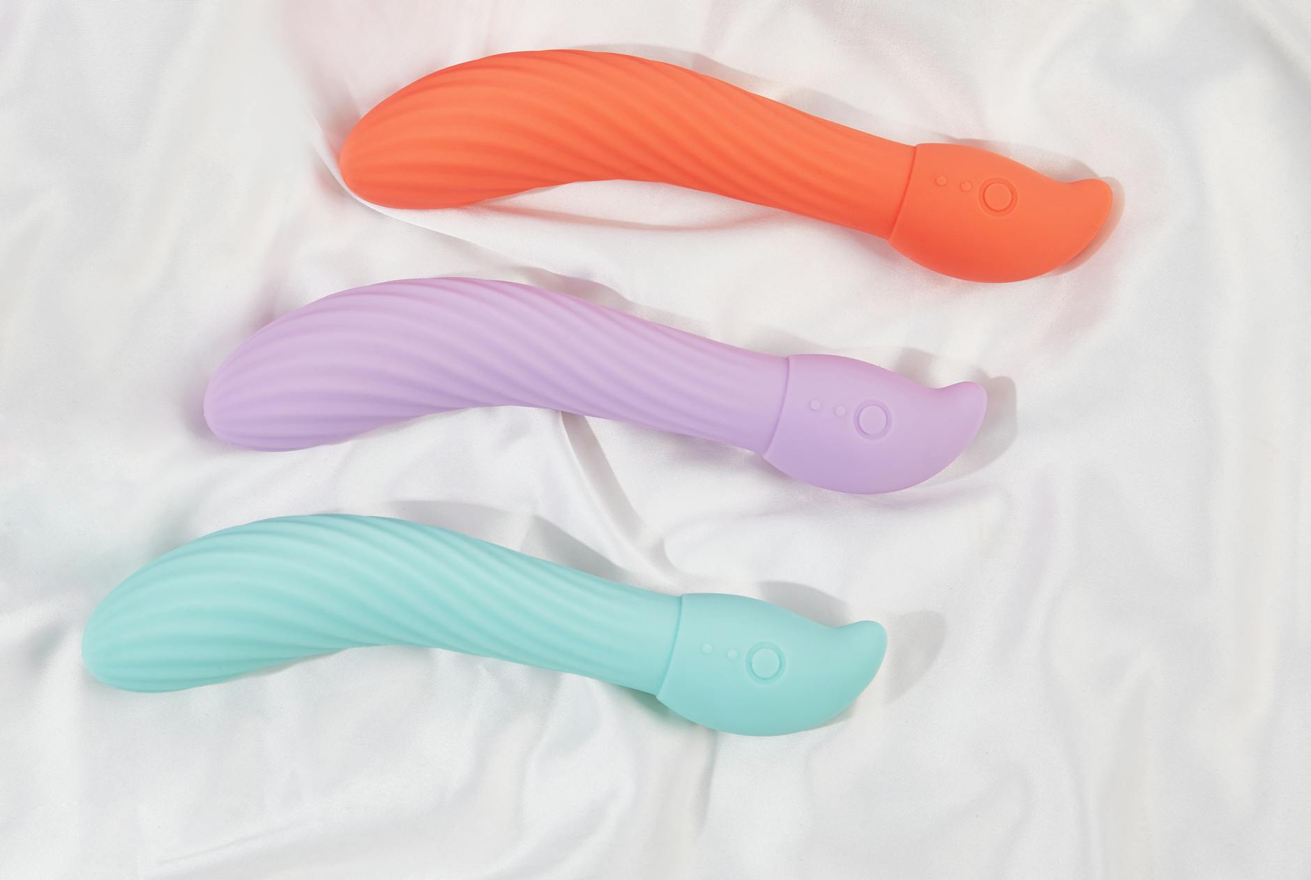 Three smooth silicone vibrators arranged on white fabric