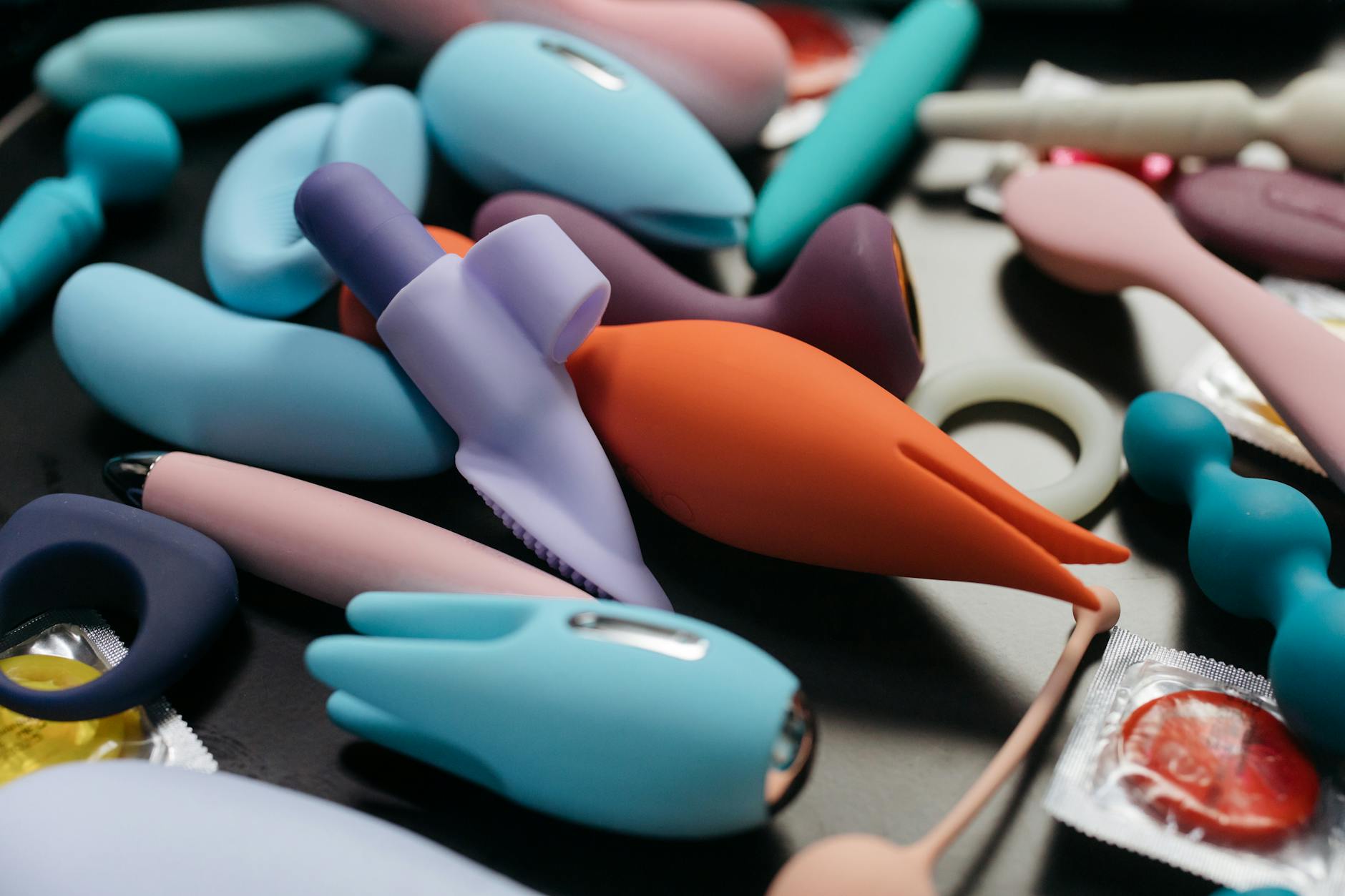 Colorful silicone vibrators arranged on dark blue fabric showcasing different pleasure options.