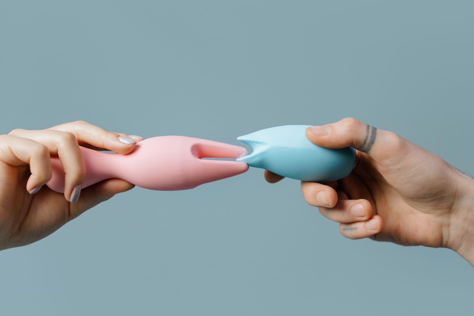 Close-up of hands holding a blue personal massager against a knitted sweater, showing gentle touch during recovery