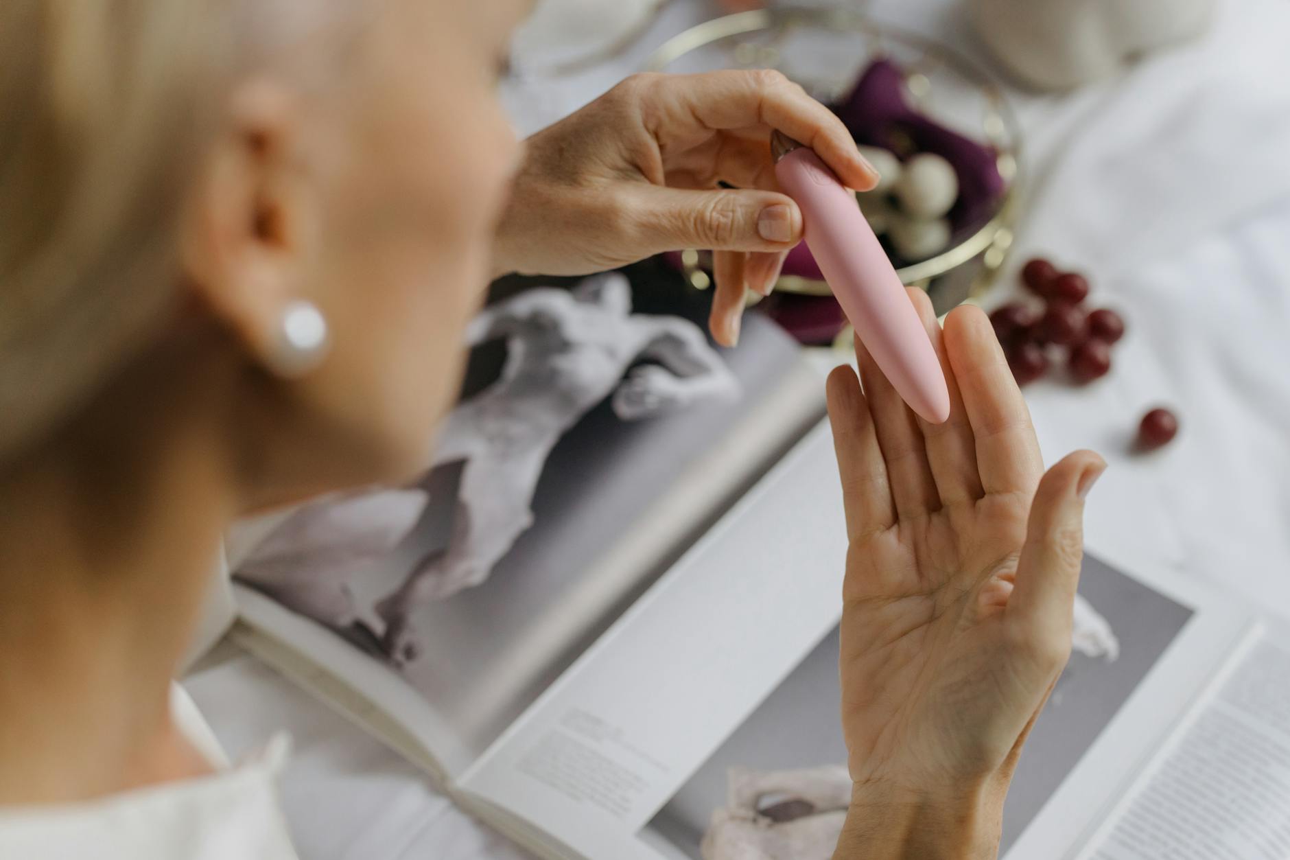 Close-up of hands exploring a pink vibrator, symbolizing reconnection with intimate sensation and self-discovery.
