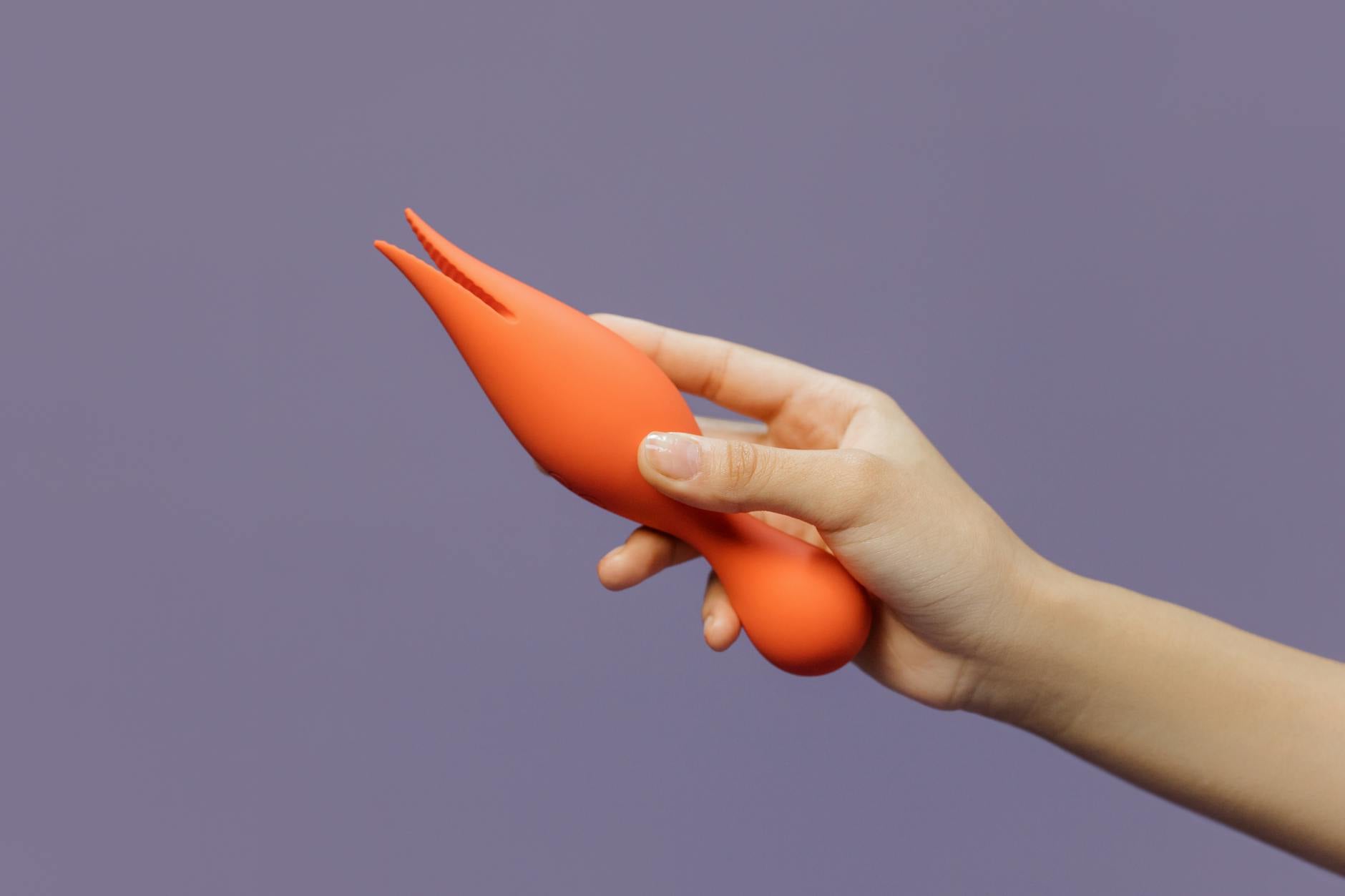 A hand holding a vibrant lemon-colored vibrator against a minimalist purple backdrop, symbolizing modern pleasure during hormonal transition.