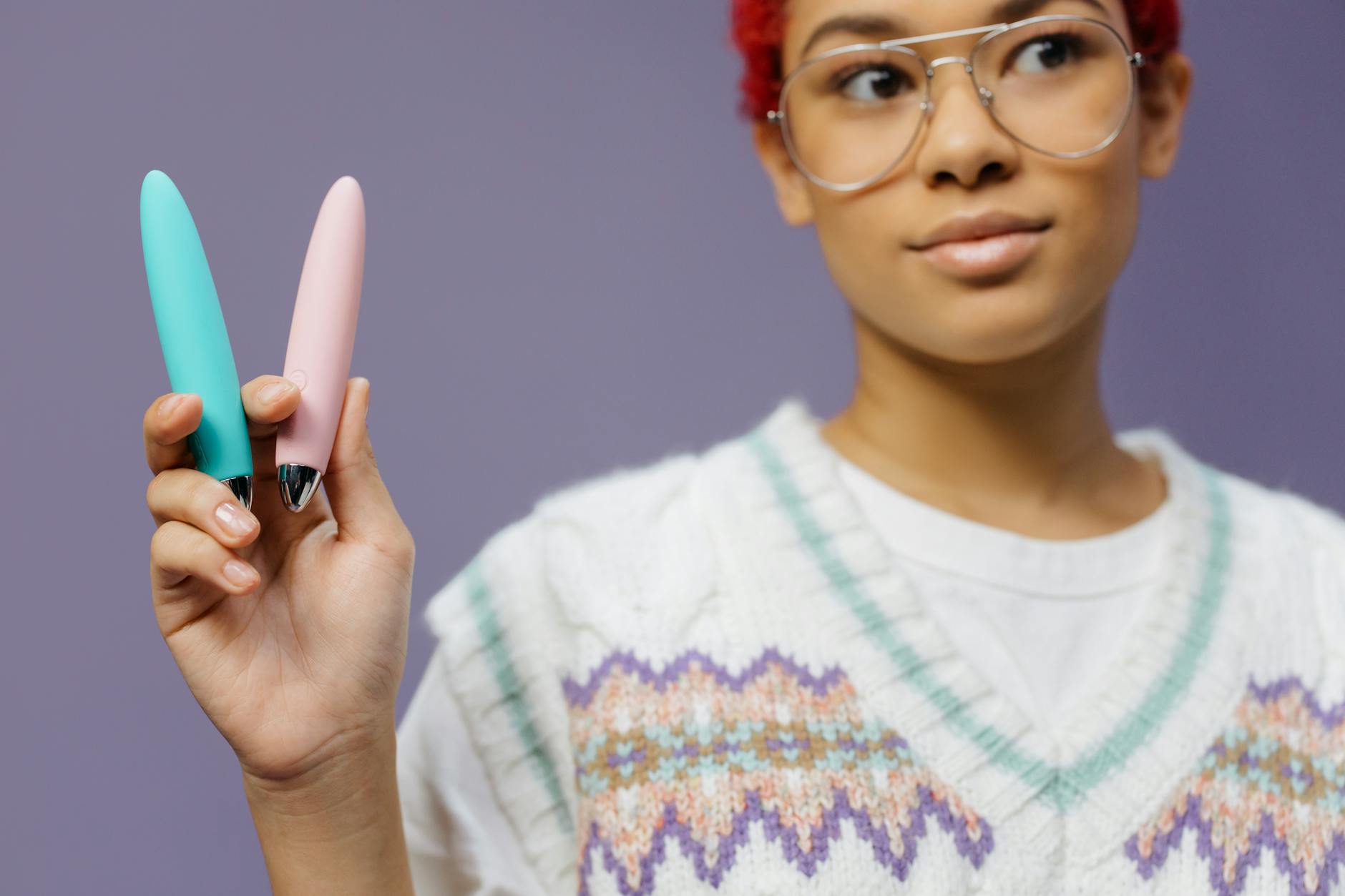 Woman holding vibrators against a purple background showing sex toy options