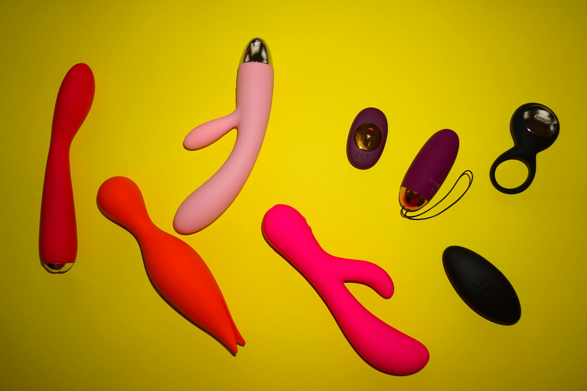 Woman holding two vibrators against a purple background, demonstrating modern pleasure products